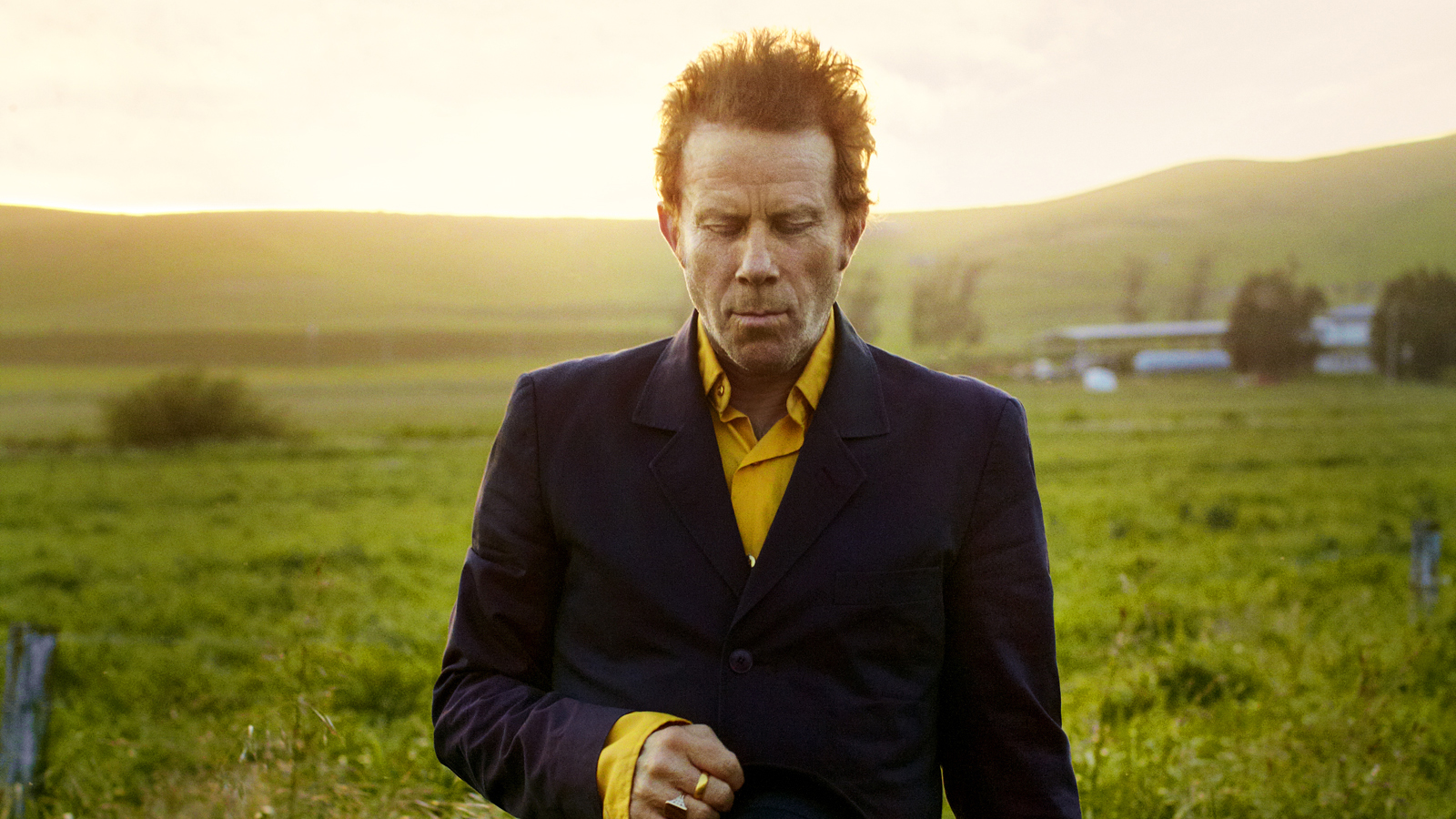 An image of musician Tom Wits walking through a field.