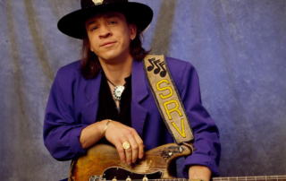 Musician Stevie Ray Vaughan standing with his signature guitar.