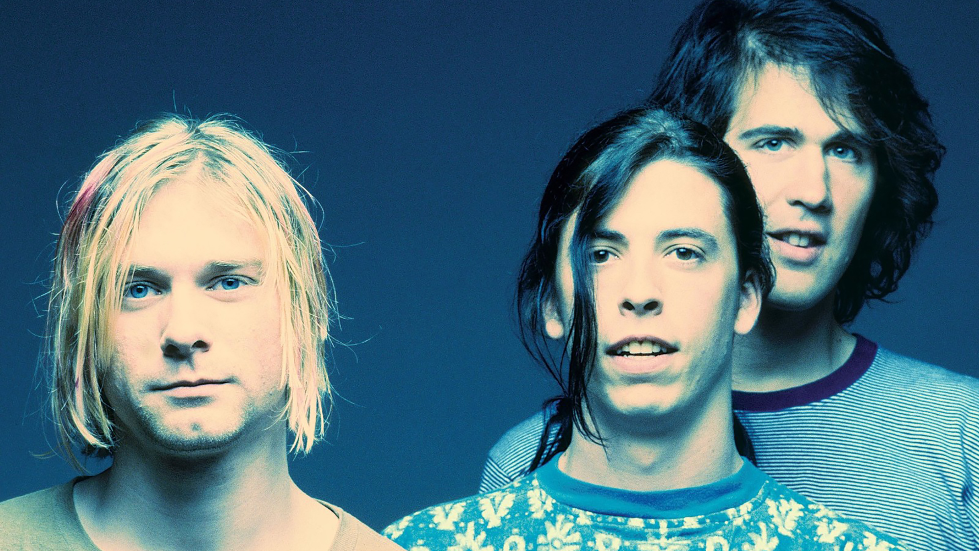 Nirvana standing in front of blue background
